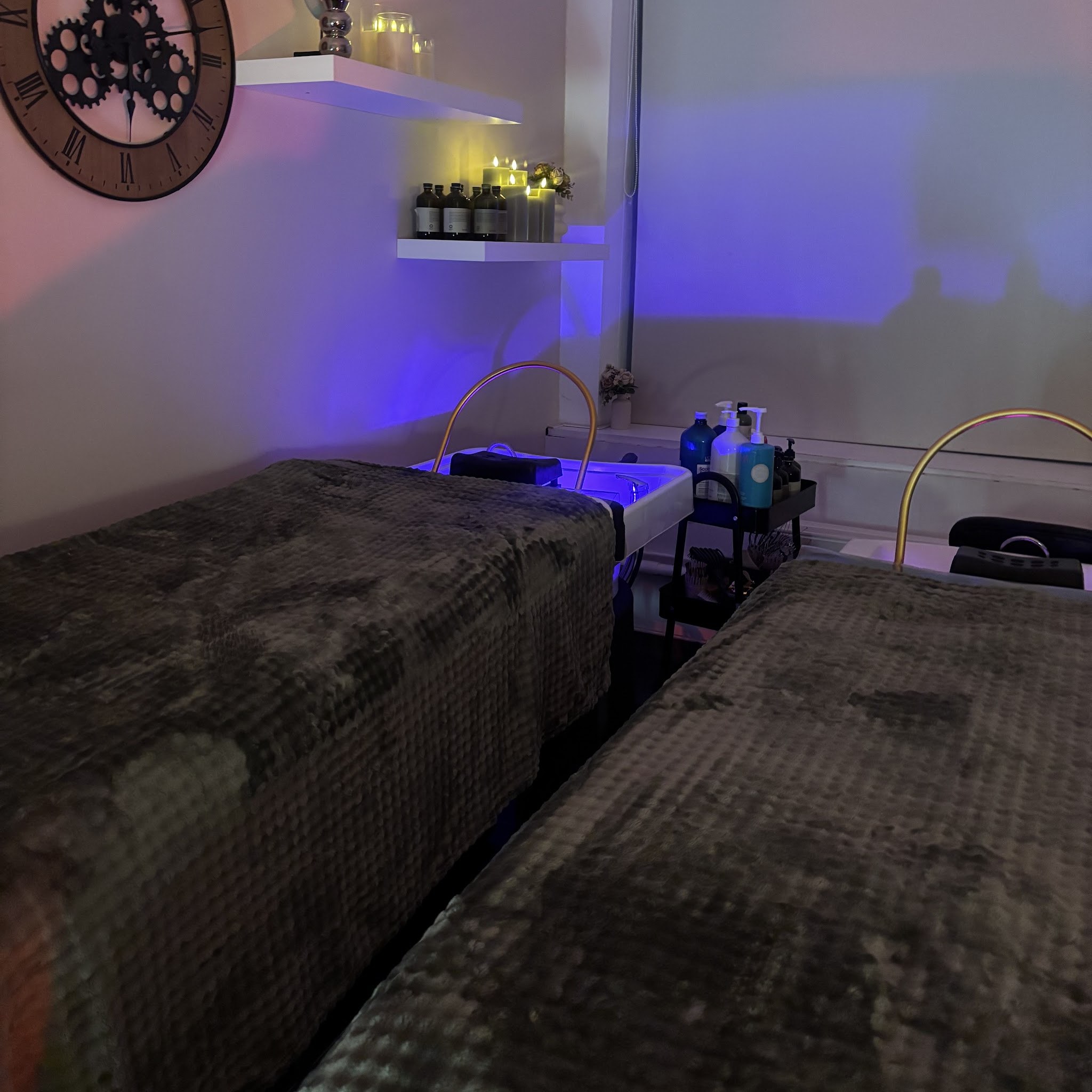 De behandelruimte in blauw licht, met een grote klok aan de muur en kaarsjes op de planken